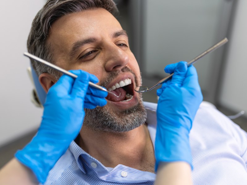A Man Receiving A Dental Cleaning, Highlighting Gum Disease Risk Factors At Walton Way Ext., Augusta, Georgia.