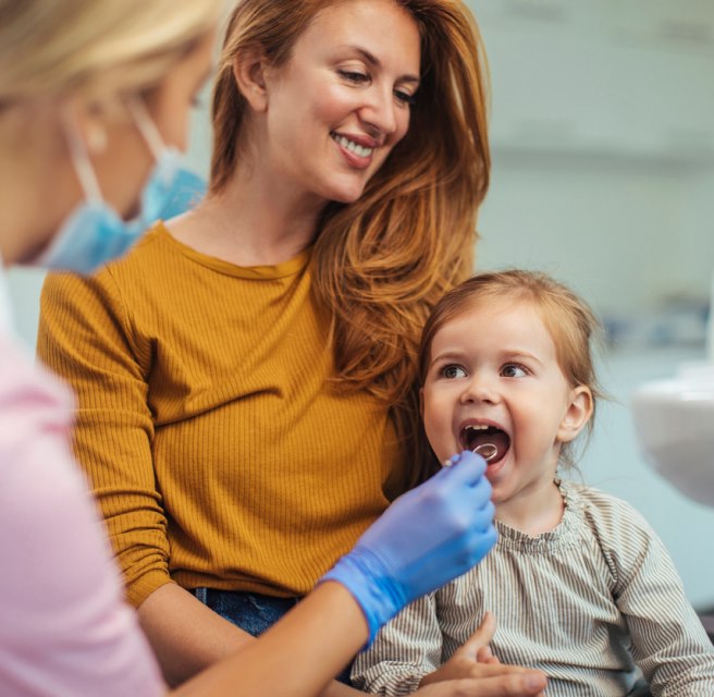 A woman holds a child's teeth as a dentist examines them during a first dental visit in Augusta, Georgia